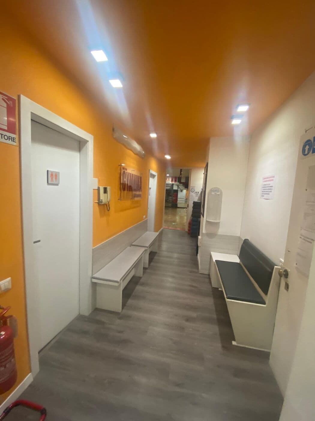 Corridoio d'ingresso arancione con panche e spogliatoi